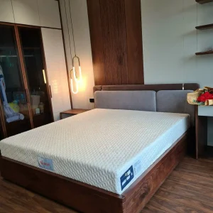 Chị Nguyễn Thu Hằng (38 tuổi, quận Hà Đông, Hà Nội) liên hệ Yêu Nệm để tìm nệm Kymdan Massage 1m6 cho hai vợ chồng. Chị nặng 54kg, trong khi chồng nặng 82kg và thường xuyên bị thoái hóa cột sống thắt lưng L4–L5, đau mỏi lưng sau khi ngủ dậy. Ban đầu, anh chị dự định chọn nệm Kymdan Massage dày 11cm để tiết kiệm chi phí. Tuy nhiên, sau khi đánh giá cân nặng của người nằm chính và tình trạng cột sống, đội ngũ Yêu Nệm tư vấn nâng lên phiên bản 13,5cm nhằm tăng độ ổn định, hạn chế cảm giác chạm đáy khi xoay trở và giúp vùng hông, vai được nâng đỡ tốt hơn. Sau khoảng 3 tuần sử dụng, anh chị phản hồi rằng giấc ngủ ổn định hơn, tình trạng đau mỏi lưng khi thức dậy giảm rõ rệt, đồng thời bề mặt massage vẫn tạo cảm giác thông thoáng, dễ chịu ngay cả trong những ngày thời tiết nóng.